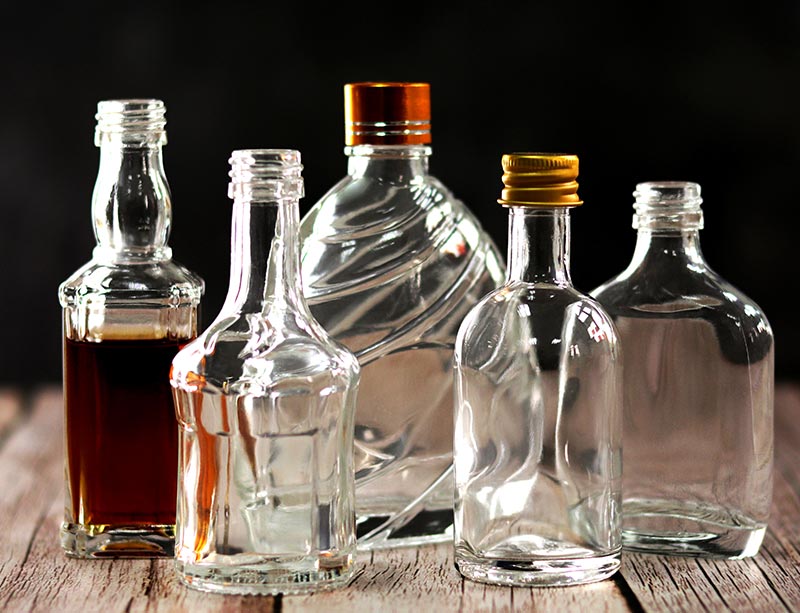 What are the advantages of using glass liquor bottles for preserving the quality and taste of beverages?